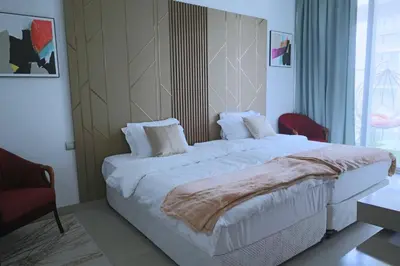 a bedroom with a large bed and a red chair at Cozy 1BR Apt in Bluebell Residences,JVC in Dubai