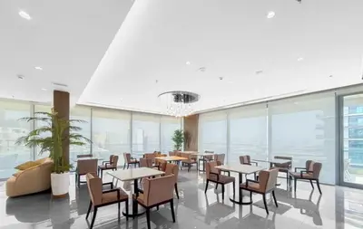 a dining room with tables and chairs and windows at Cozy 1BR Apt in Bluebell Residences,JVC in Dubai