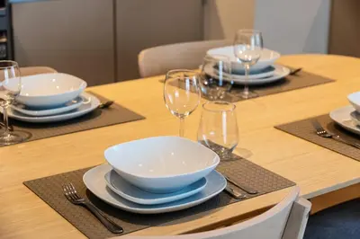 a wooden table with plates and bowls and wine glasses at Bright and Stylish 2BD at Creek Beach, Sleeps 4 in Dubai