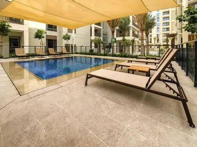 a swimming pool with two lounge chairs and an umbrella at Bright and Stylish 2BD at Creek Beach, Sleeps 4 in Dubai