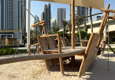 a swing on the beach with a city in the background at Bright and Stylish 2BD at Creek Beach, Sleeps 4 in Dubai