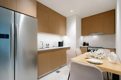 a kitchen with a wooden table and a refrigerator at Luxury Apt and Private Beach with cooled sand in Dubai