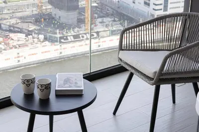 a table with two cups and a book and a chair at New Studio in Business Bay with private Jacuzzi in Dubai