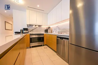 a kitchen with white cabinets and a stainless steel refrigerator at Luxury Escapes - Exquisite 3BR plus Maid, Full Sea View in JBR in Dubai