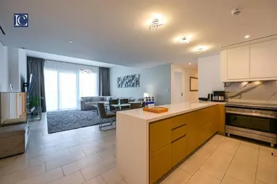 a kitchen with a counter and a living room at Luxury Escapes - Exquisite 3BR plus Maid, Full Sea View in JBR in Dubai