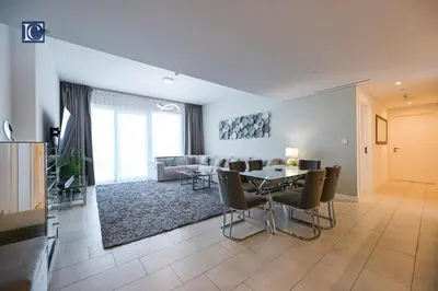 a living room with a table and chairs and a couch at Luxury Escapes - Exquisite 3BR plus Maid, Full Sea View in JBR in Dubai