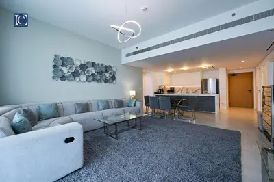 a living room with a couch and a table and a kitchen at Luxury Escapes - Exquisite 3BR plus Maid, Full Sea View in JBR in Dubai