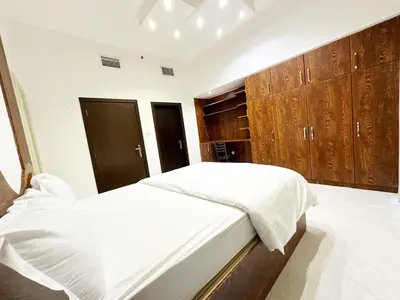 a bedroom with a white bed and wooden cabinets at 1Bedroom Apartment with Portable bed in Living Area in Dubai