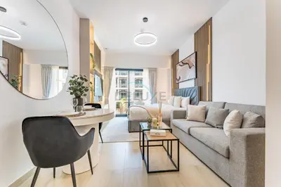 a living room with a couch and a table at Pool and Community View Studio with Balcony Near Park, Pantheon Elysee III, Jumeirah Village Circle by Deluxe Holiday Homes in Dubai