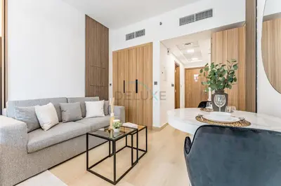 a living room with a couch and a table at Pool and Community View Studio with Balcony Near Park, Pantheon Elysee III, Jumeirah Village Circle by Deluxe Holiday Homes in Dubai
