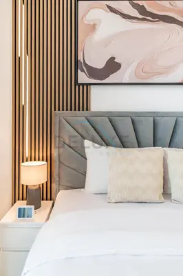 a bedroom with a white bed and a painting at Pool and Community View Studio with Balcony Near Park, Pantheon Elysee III, Jumeirah Village Circle by Deluxe Holiday Homes in Dubai
