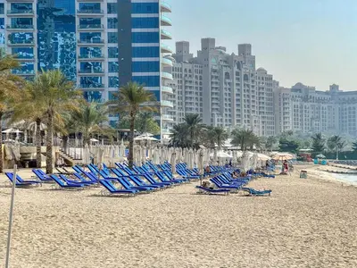 a group of chairs and umbrellas on a beach at Family Beach Home 3BR on Palm Jumeirah with Pool in Dubai