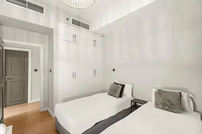 a white bedroom with two beds and a chandelier at Dubai Marina Luxury 2BR with Pool, Gym & Near JBR Beach, Metro in Dubai