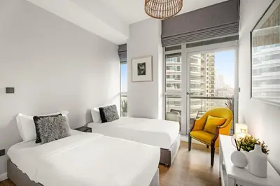 a bedroom with two beds and a yellow chair at Dubai Marina Luxury 2BR with Pool, Gym & Near JBR Beach, Metro in Dubai