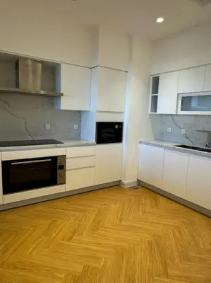 a kitchen with white cabinets and a wooden floor at 5 Star Luxury 3BR Apartment on The Palm with Huge Pool and Beach in Dubai
