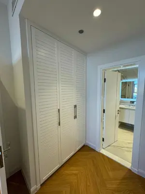a room with a closet with white doors and wood floors at 5 Star Luxury 3BR Apartment on The Palm with Huge Pool and Beach in Dubai
