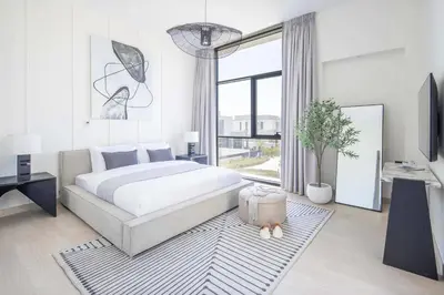 a white bedroom with a bed and a large window at Frank Porter - Murooj Al Furjan West in Dubai