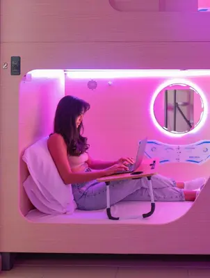 a woman sitting on a bed with a laptop at Berloga Holiday Homes JBR in Dubai