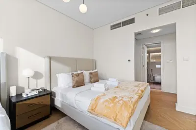 a white bedroom with a large bed and a table at Luxury Apt DIFC, XL Layout, Pool, Gym, Skyline View in Dubai