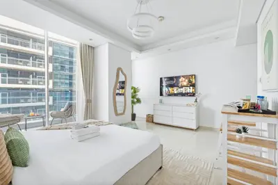 a white bedroom with a bed and a tv at Cozy Studio 7 Minutes From Dubai Mail in Dubai