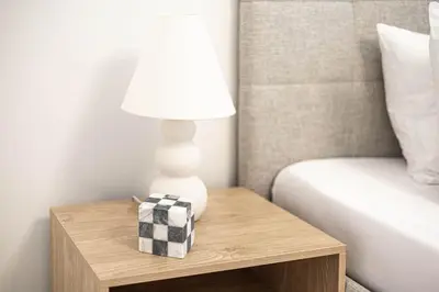 a lamp on a wooden table next to a bed at Cozy Studio 7 Minutes From Dubai Mail in Dubai