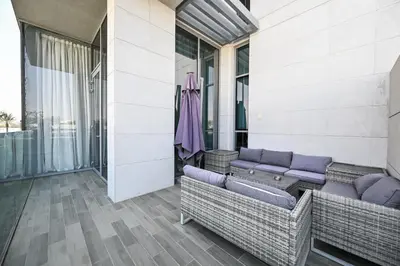 a balcony with wicker furniture on a building at Relax in Style 2BR Huge Terrace Lagoon Access in Dubai