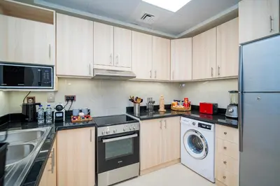 a kitchen with wooden cabinets and a washer and dryer at Oasis by Tarrab in Dubai