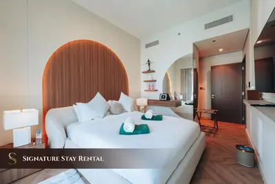 a hotel room with a white bed and a kitchen at Stylish 2-Bedroom Luxury Stay in Downtown Dubai with Burj Khalifa & Fountain Views in Dubai