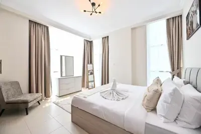 a white bedroom with a large bed and a chair at Scala Tower- Business Bay Dubai - Luxury Apartments by Canvas Holiday Homes in Dubai