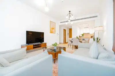 a living room with white furniture and a flat screen tv at Escape24 Elegant 2BR with Canal view near Safa Park in Dubai