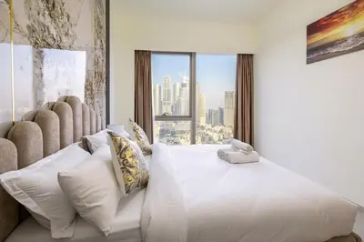 a bedroom with a large white bed with a window at Grande 2BR Apartment with Burj Khalifa & Fountain Views in Dubai