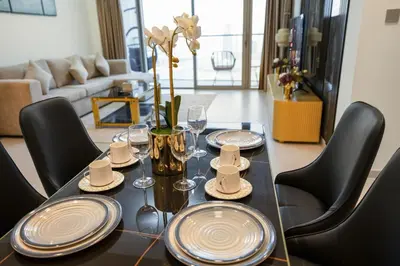 a dining room table with plates and wine glasses at Grande 2BR Apartment with Burj Khalifa & Fountain Views in Dubai
