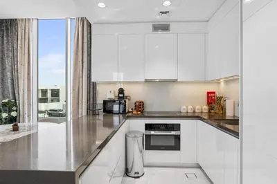 a kitchen with white cabinets and a large window at Luxurious 1 BR in District One Beach Access in Dubai