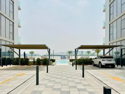 a parking lot with a car parked under two buildings at Luxurious 1 BR in District One Beach Access in Dubai