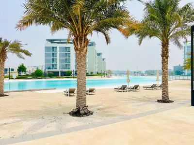 a group of palm trees on a beach with a pool at Luxurious 1 BR in District One Beach Access in Dubai
