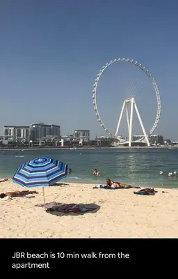 a beach with a ferris wheel and people laying on the beach at Luxury Apartment- 5 min Walking Distance Beach and 3 minutes walking distance Metro in Dubai