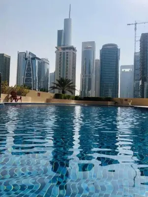 a swimming pool with a city skyline in the background at Luxury Apartment- 5 min Walking Distance Beach and 3 minutes walking distance Metro in Dubai