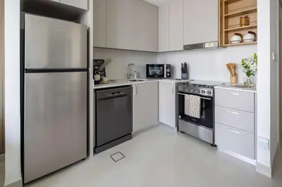 a kitchen with stainless steel appliances and white cabinets at Frank Porter - Creek Crescent Tower 1 in Dubai
