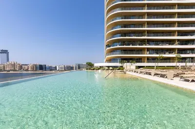 a large pool of water next to a large building at Maison Privee - Coastal Living with Uninterrupted Sea & Palm Views in Dubai