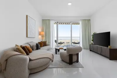 a living room with a couch and a tv at Maison Privee - Coastal Living with Uninterrupted Sea & Palm Views in Dubai
