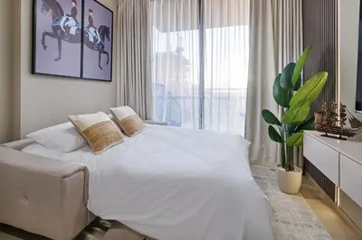 a bedroom with a white bed and a large window at Luxury 1BR JVC Pool & Balcony by Circle Mall in Dubai