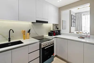 a kitchen with white cabinets and a black stove top oven at Luxury 1BR JVC Pool & Balcony by Circle Mall in Dubai