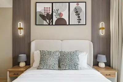 a bedroom with a white bed with two lamps and two tables at Luxury 1BR JVC Pool & Balcony by Circle Mall in Dubai