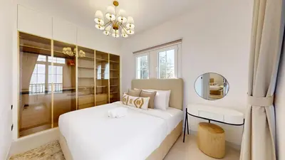 a white bedroom with a bed and a chandelier at Ranches 1 Upgraded Three Bedroom Villa in Dubai