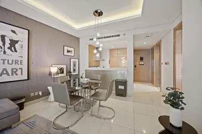 a dining room and living room with a table and chairs at Elite Escapes - Glamorous 1BR DAMAC Paramount B in Dubai