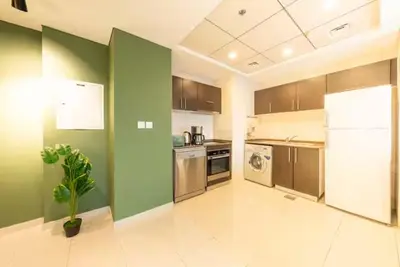 a large kitchen with green walls and a refrigerator at Charming Stay by Dubai Marina in Dubai