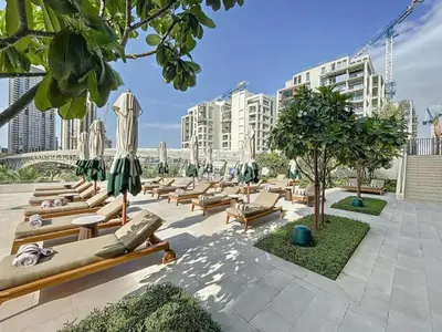 a row of lounge chairs with umbrellas and trees at Modern 2BR Apartment - Vida Residences Creek Beach - Creek Beach Access in Dubai