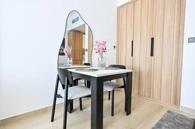 a dining room with a table and a mirror at Chic Studio in Prime JVC Spot - Holiday Boulevard in Dubai