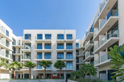 an apartment building with palm trees in front of it at Chic Studio in Prime JVC Spot - Holiday Boulevard in Dubai