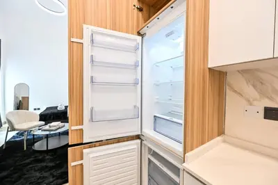 an empty refrigerator with its door open in a room at Modern Studio with Balcony and Pool Access - Holiday Boulevard in Dubai
